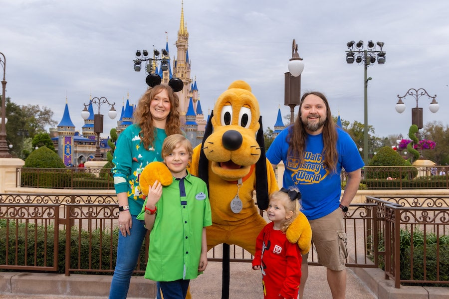 Image of Pluto, family, and child dressed as Disney Cast Member at Magic Kingdom Park