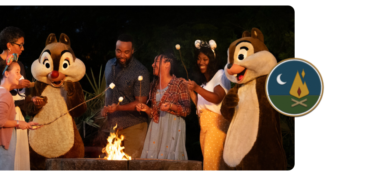 A family roasts marshmallows around a campfire with Chip 'n Dale. 